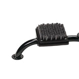 A close-up of a black metal footrest with a rectangular black bristle pad, likely for a massage table or pedicure station, on a light gray background.